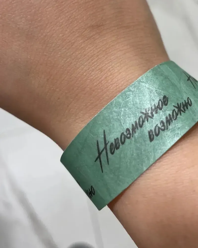 Браслет с концерта на руке, на нём надпись «Невозможное возможно»